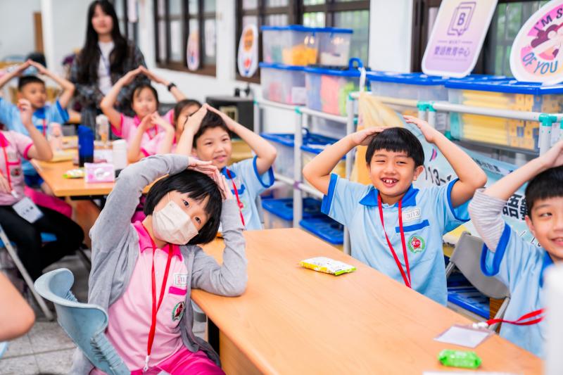 問題是「Please act like a building.」，大小學伴做裝成是建築物的動作。