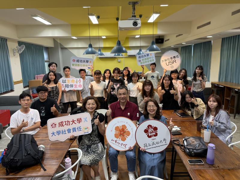 講師與學伴成員於教室內合影，大家手持標語牌，展現團隊活力與合作精神。